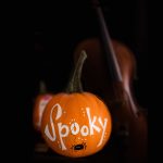 Pumpkin with Spooky painted on it and violin in background